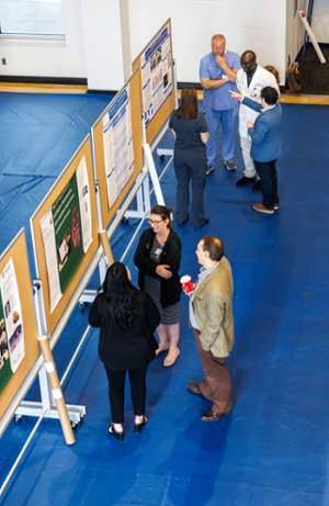 Faculty and staff from various departments on UMMC's campus discussing one of the research posters.